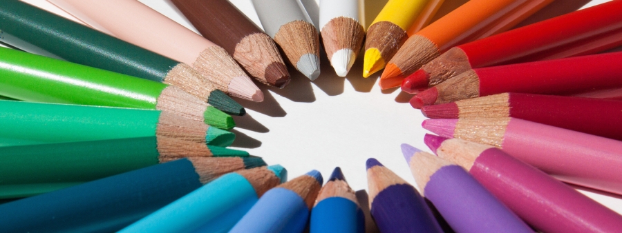Sinnbild für Farben: Verschiedene bunte Holzmalstifte liegen in einem Kreis.